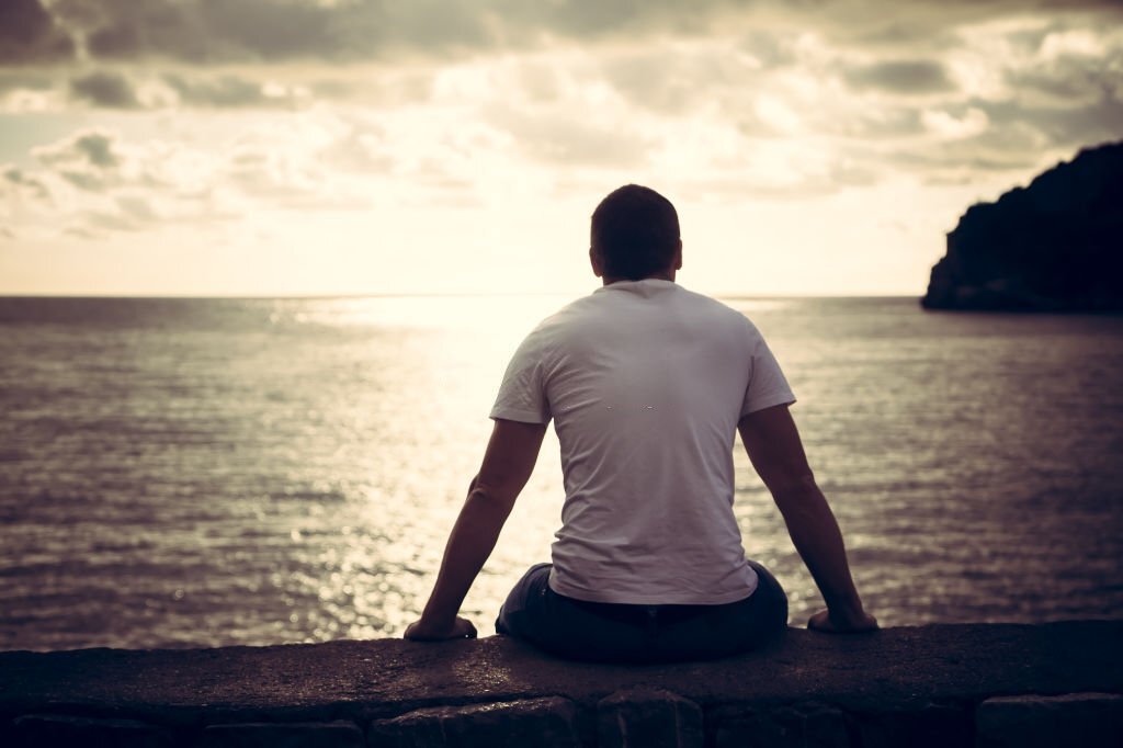 A man sitting at the beach, sun watching