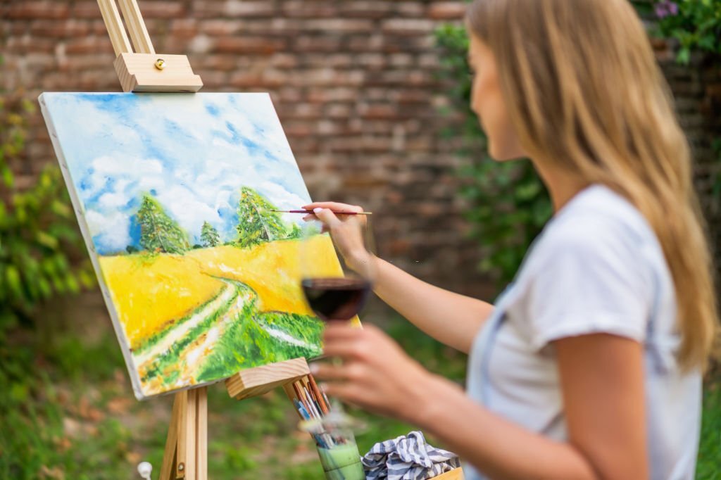 A woman enjoying painting and sipping wine