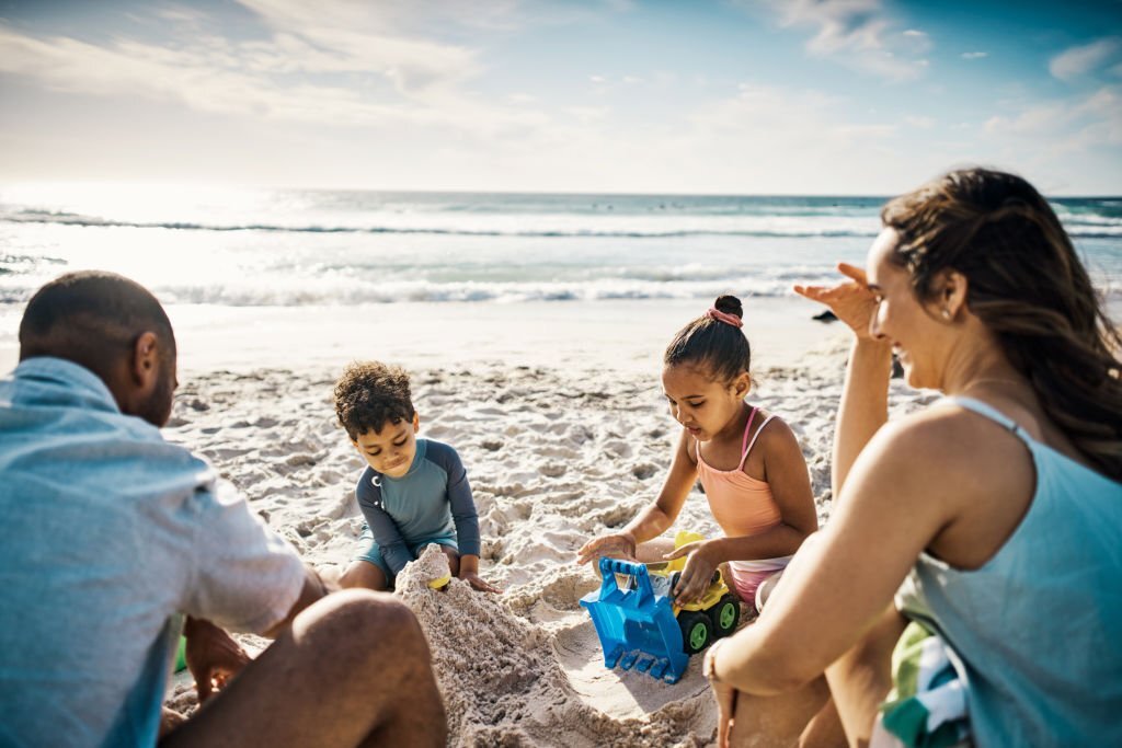 A Family sitting on the beach engaged in a beach activity and having fun