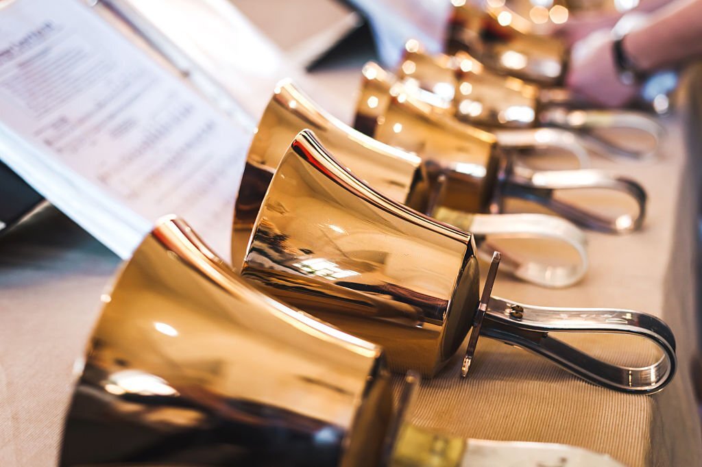 Golden handbells on table with sheet of notes on Yoruba christmas hymns