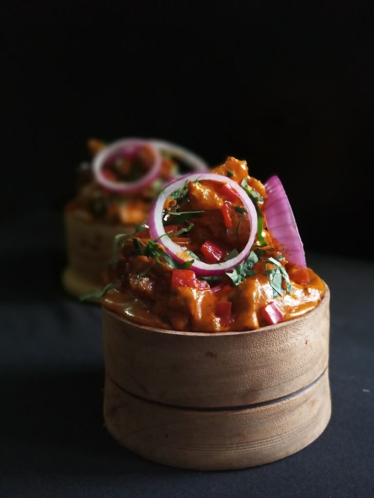 Nkwobi, garnished with onion rings, served in a small calabash