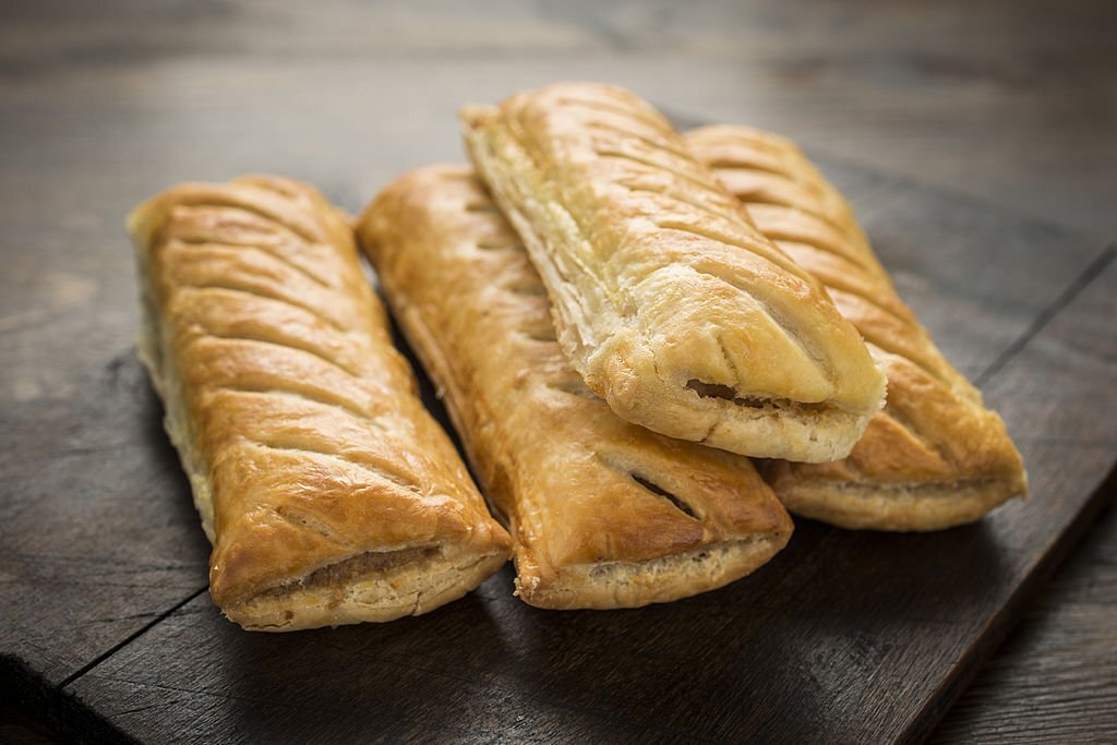 four Sausage Rolls on wood Table.