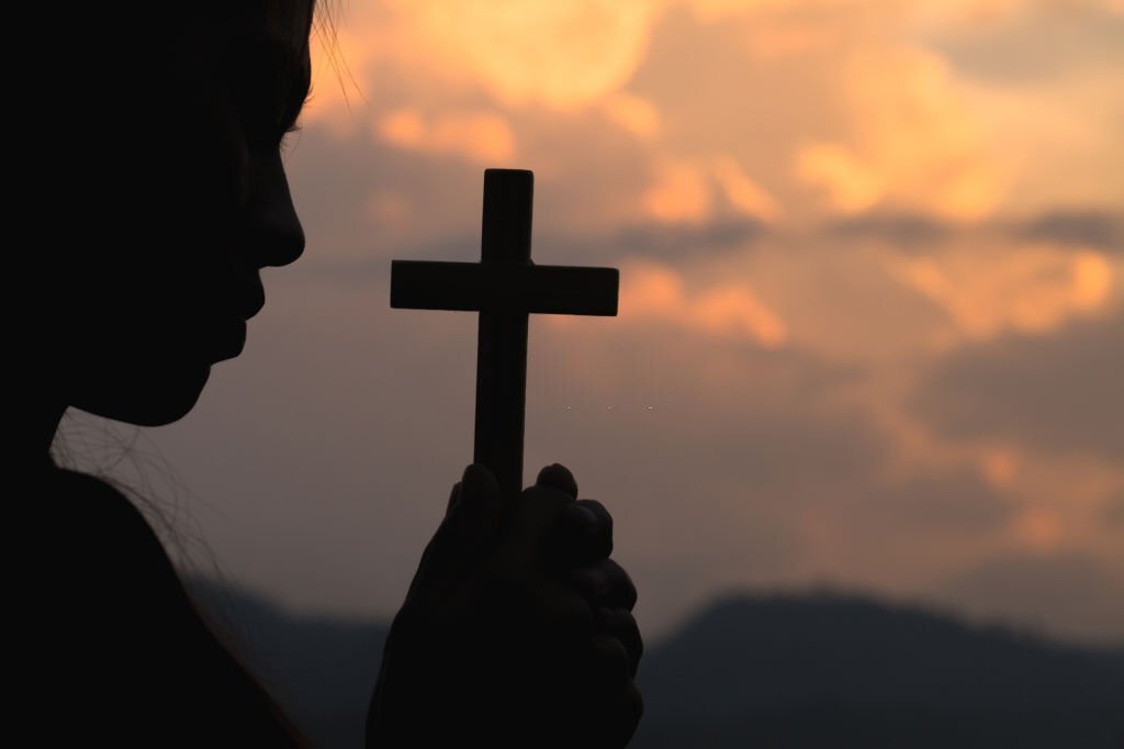 Woman-hands -holding-wooden-cross -on-sunrise